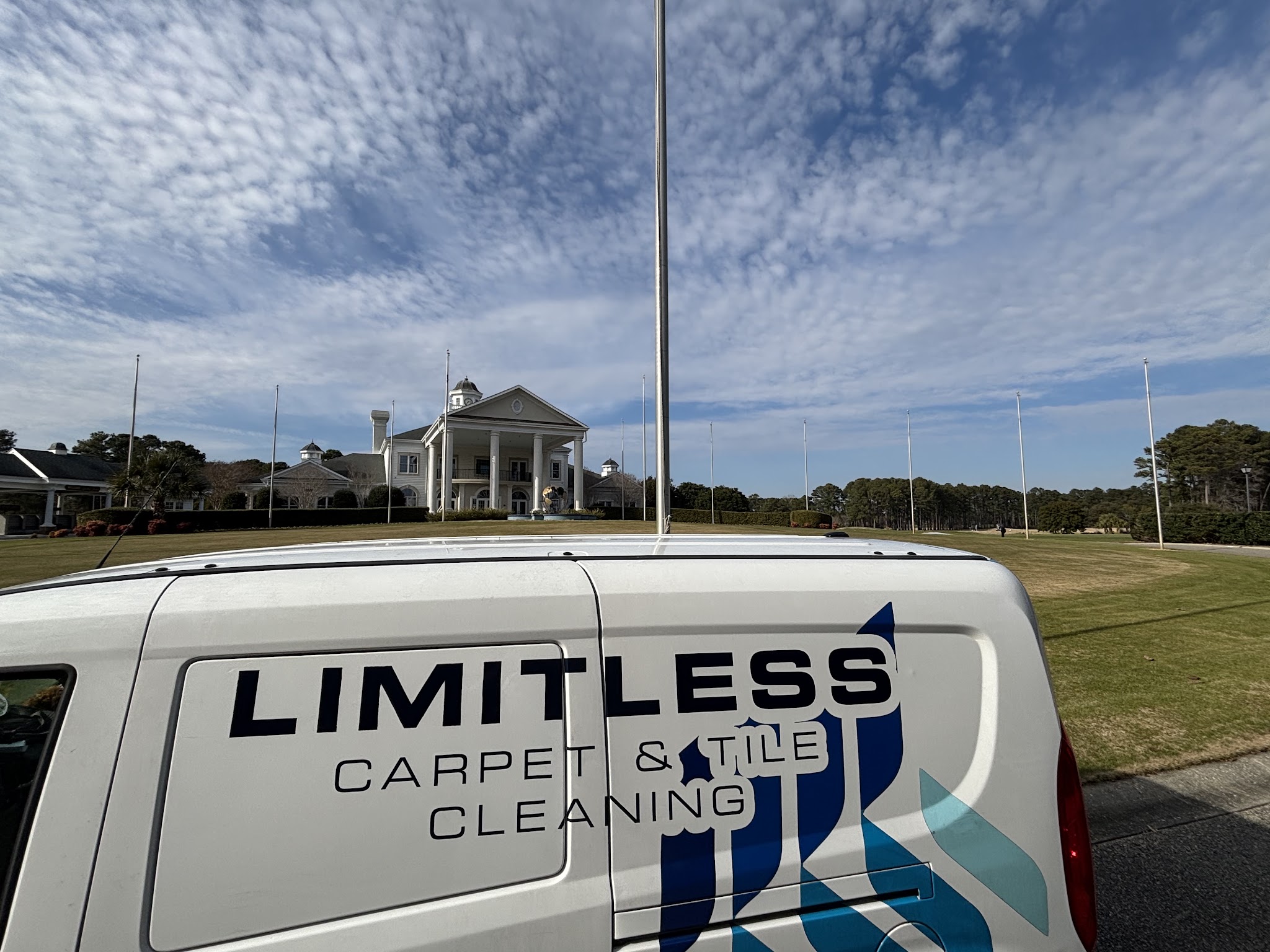 Our Limitless Carpet and Tile Cleaning van parked in front of a large white columned clubhouse